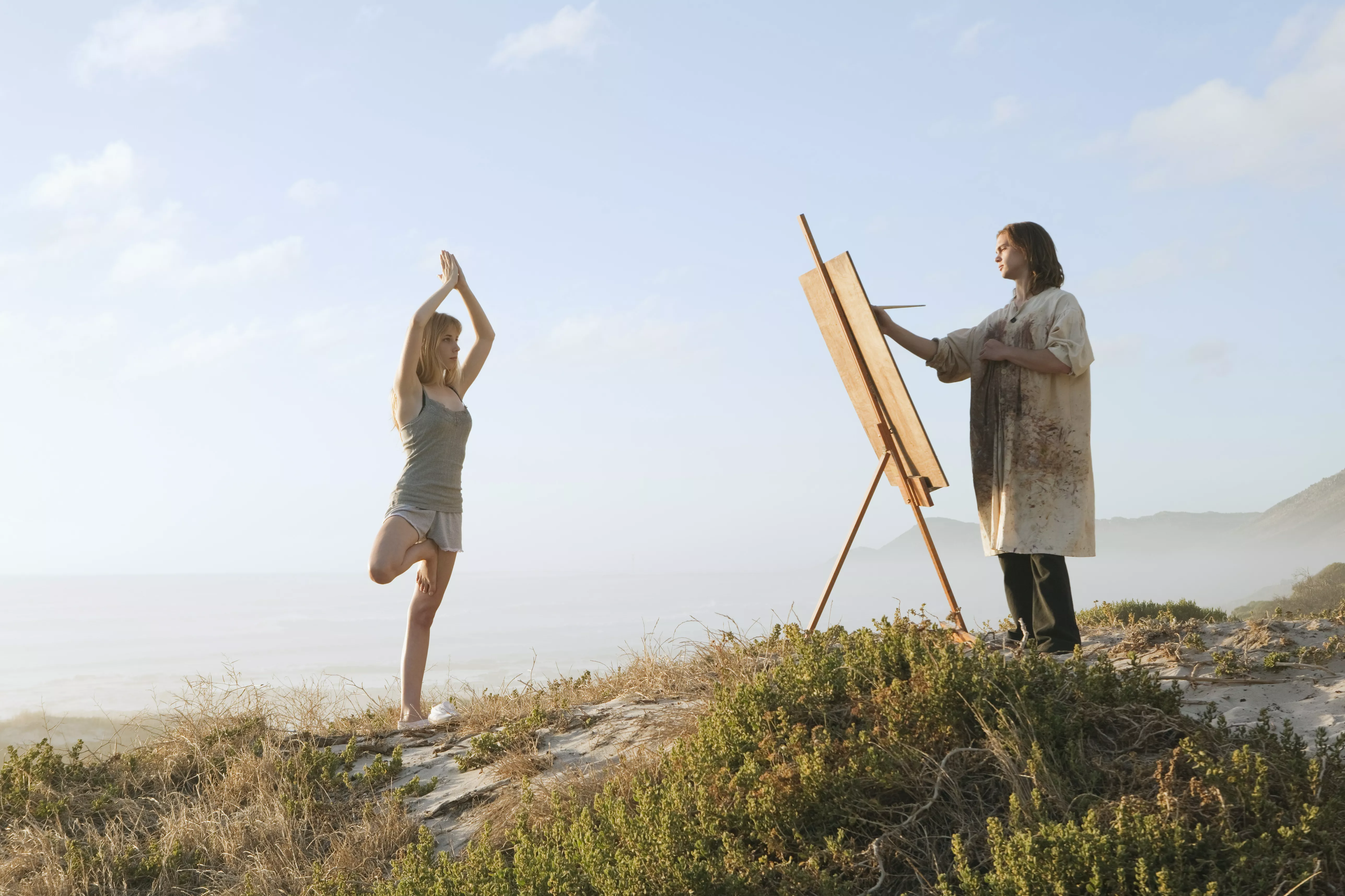 Young man painting girl in landscape